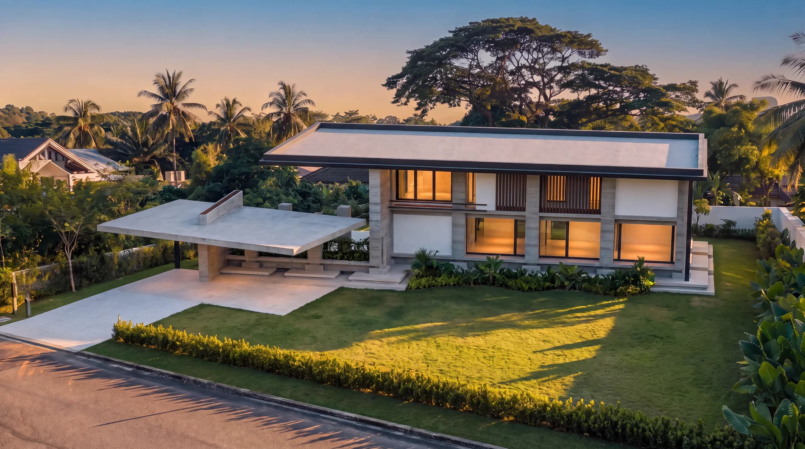 The finished house on the plot at dusk, lawn and driveway laid and the interior lights on